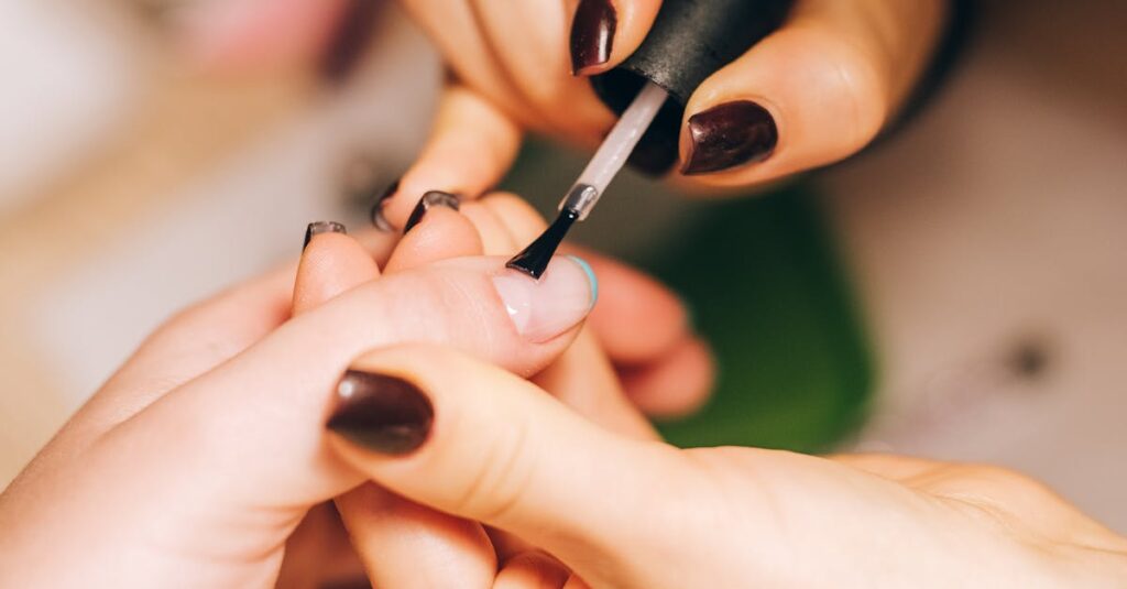 Close-up of a manicurist applying nail polish during a professional manicure session.